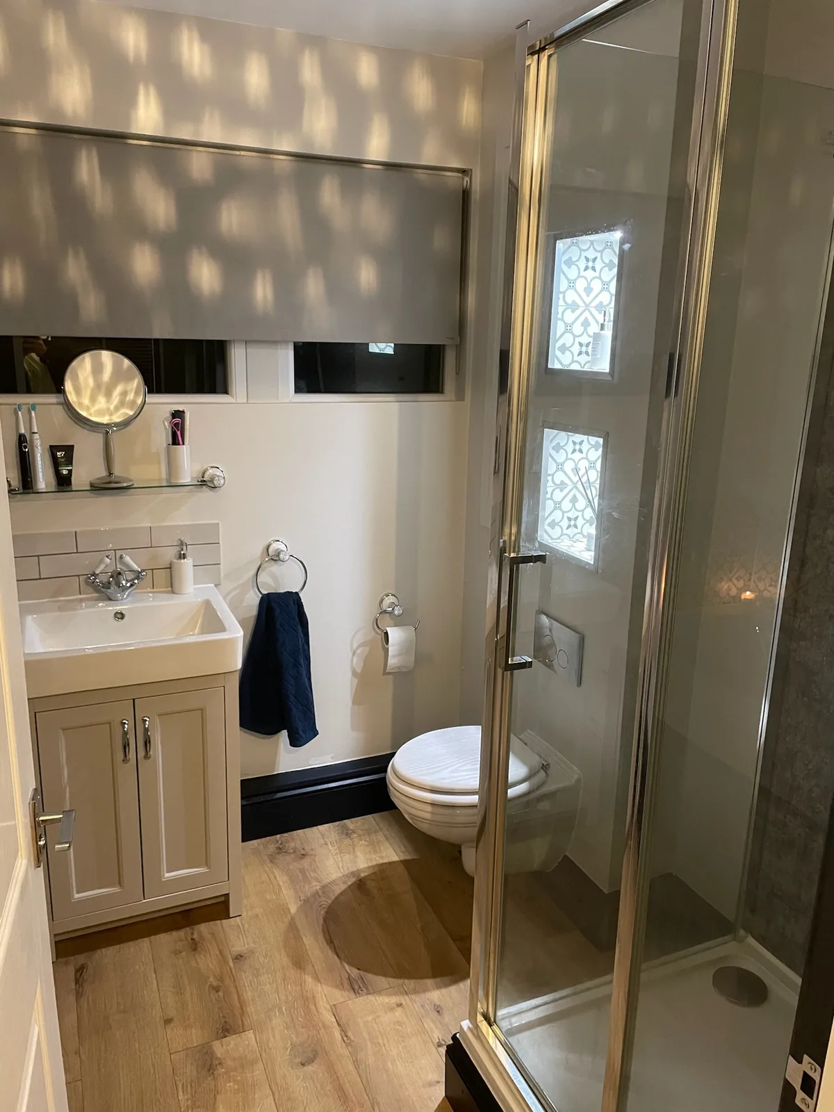 Bathroom with corner shower enclosure, wall-hung WC and wood-effect flooring