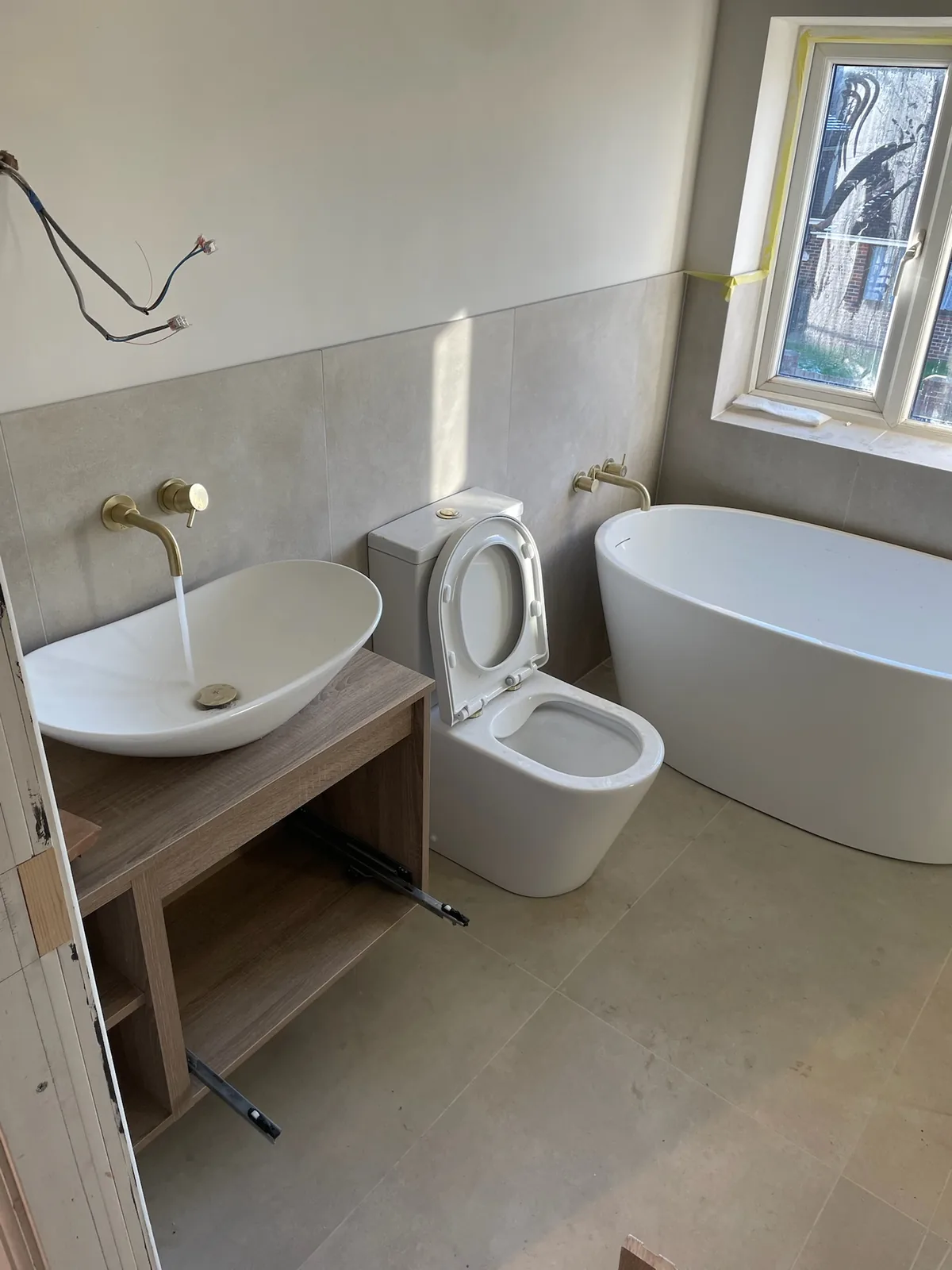 Bathroom with freestanding bath, oval vessel basin and brushed brass taps